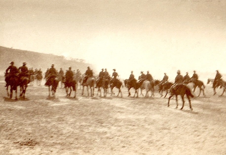 A historical sepia-toned scene of mounted soldiers on horseback in a barren landscape.