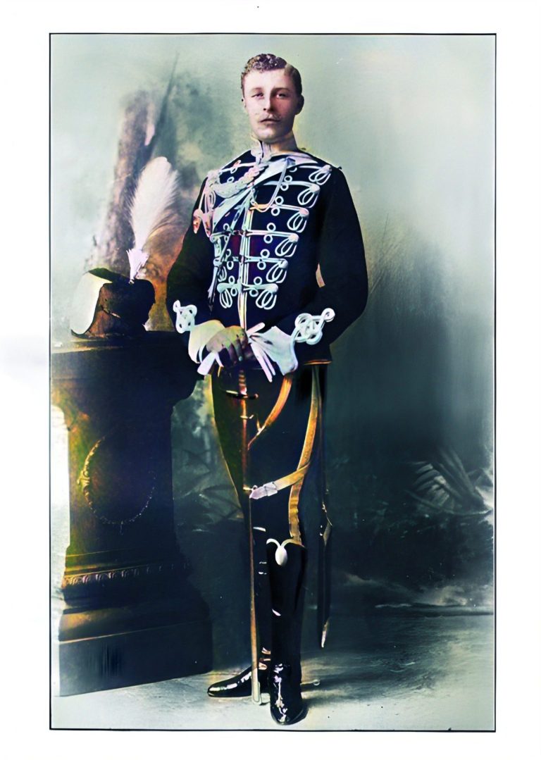 A man in ornate historical uniform stands with a sword near a decorative pillar.