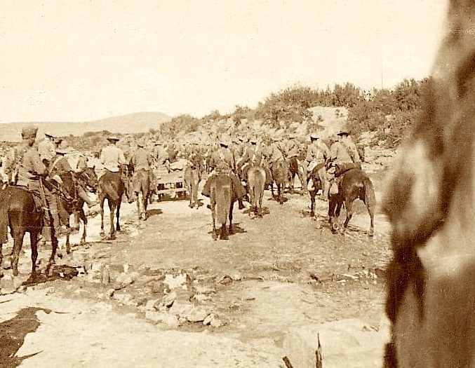 A sepia-toned scene of soldiers on horseback in a rugged landscape.