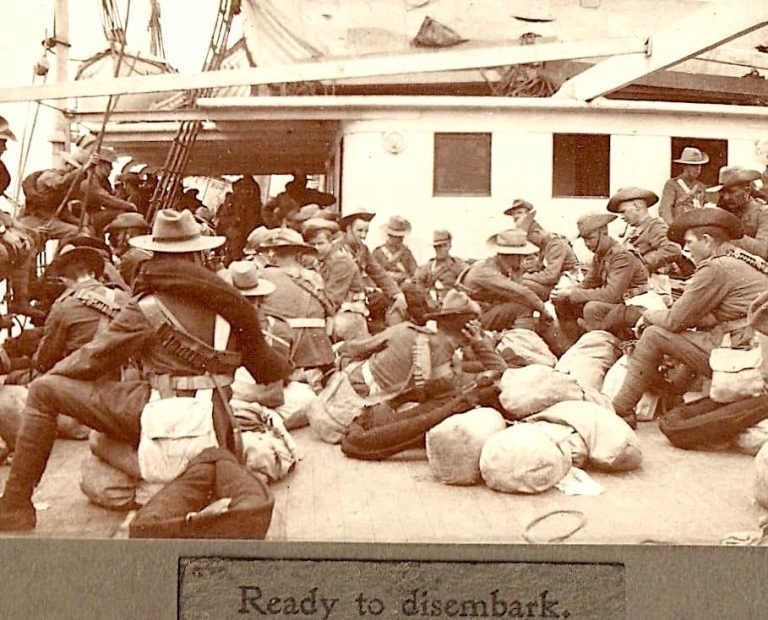 Troops seated on deck preparing to disembark, surrounded by bags and equipment.