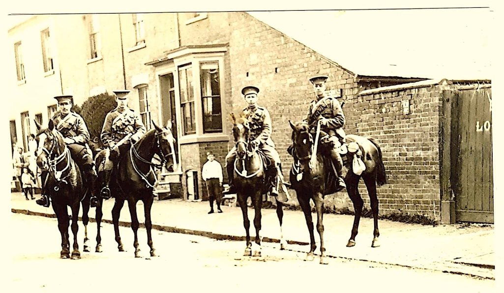 Four mounted Warwickshire  Yeoman in uniforms, sitting on horseback on a street.