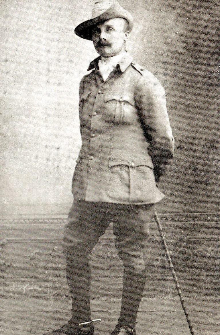 A man in military uniform stands with a cane, wearing a slouch hat.
