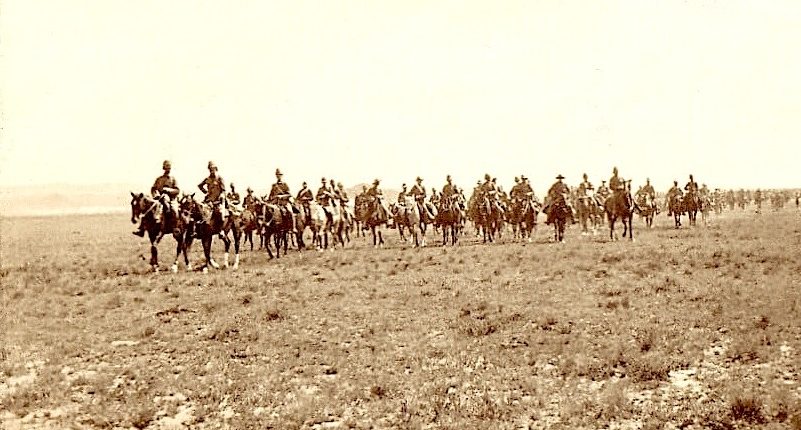 A line of soldiers on horseback riding across an open landscape.