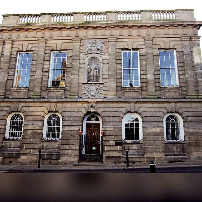 Historic stone building with ornate details and tall windows, featuring a central entrance.
