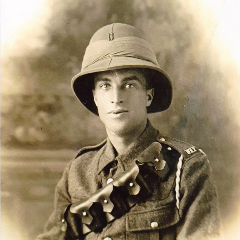 A young soldier in a military uniform and pith helmet, posed against a soft background.