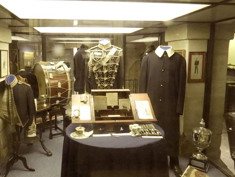 Display of historical clothing and trophies in a museum setting.